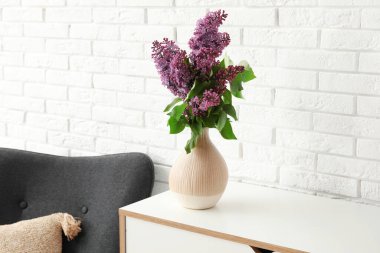 Açık tuğla duvarın yanındaki çekmecelerde güzel leylak çiçekleri olan vazo.