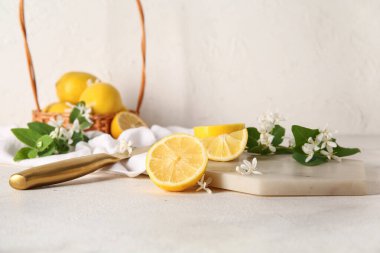 Beyaz masanın üzerinde çiçek açan dalları olan bir sepet limon.