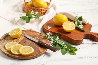 Beyaz masada çiçek açan dalları olan tahtalar ve limon sepeti.