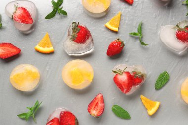 Taze çilek ve gri arka planda donmuş portakal parçaları.