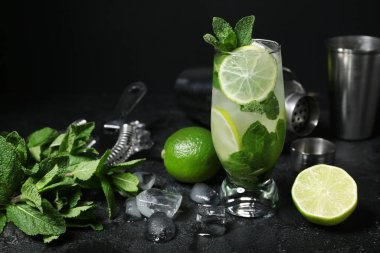 Bir bardak soğuk mojito ve koyu arkaplanda malzemeler.