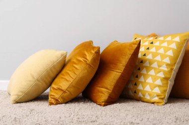 Halıda şık yastıklar, ışık duvarının yanında.