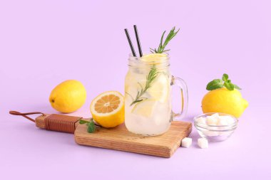 Ahşap pano ve eflatun arkaplanda taze limonata bulunan mason kavanozu.