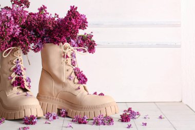 Şık kadın ayakkabıları ve açık duvarın yanında güzel leylak çiçekleri olan kompozisyon