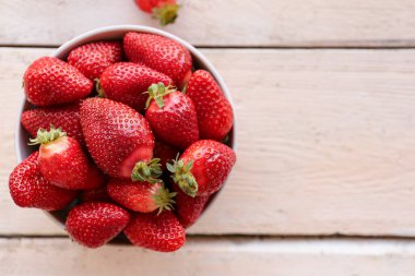 Beyaz ahşap masada taze çilek kasesi.