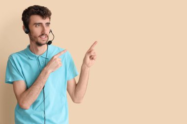 Erkek teknik destek ajanı bej arka plandaki bir şeyi işaret ediyor