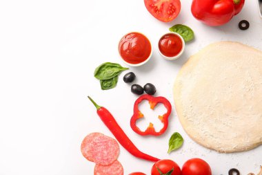 Beyaz arka planda pizza hazırlamak için ham hamur ve malzemeler