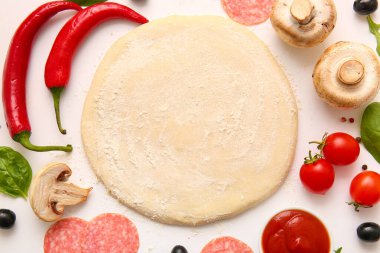 Beyaz arka planda pizza hazırlamak için ham hamur ve malzemeler