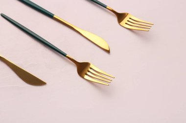 Beyaz arka planda yeşil saplı altın çatallar ve bıçaklar