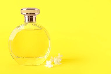 Güzel leylak çiçekleri ve sarı arka planda bir şişe parfüm.