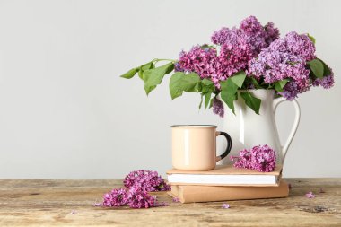 Sürahi güzel leylak çiçekleri, kahve ve kitaplarla beyaz duvarın yanındaki ahşap masada.