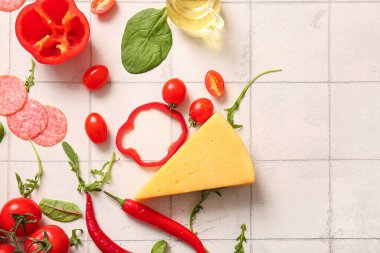 Beyaz fayanslı pizza hazırlamak için farklı malzemeler.