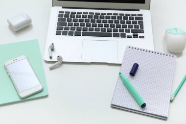 Beyaz arkaplanda dizüstü bilgisayar, defter ve telefon kompozisyonu