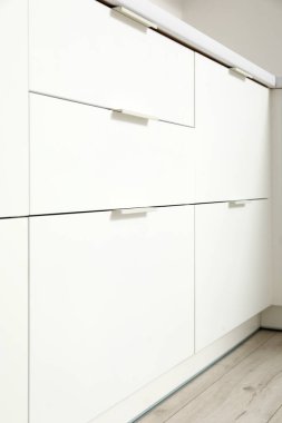 Açık mutfakta çekmeceleri olan beyaz tezgâhlar.