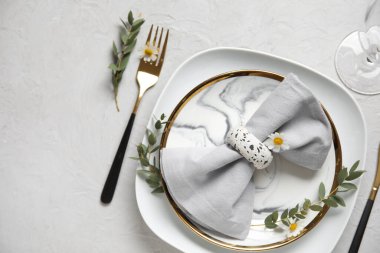 Katlanmış peçeteli tabaklar, altın çatal bıçak takımı ve grunge beyaz arka planda cam.