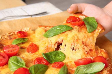 Kadın eli, parşömen üzerinde lezzetli bir pizza margaritası alıyor, yakın plan.