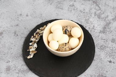 Kaynamış bıldırcın yumurtası ve gri arka planda kabukları olan bir pano.