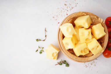 Beyaz zemin üzerinde İsviçre peyniri ve domates parçaları olan bir kase.