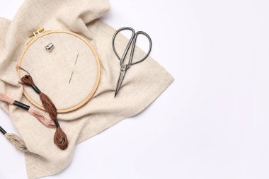 Beyaz arkaplanda izole edilmiş bez, makas ve küf iplikleriyle nakışlı halka.