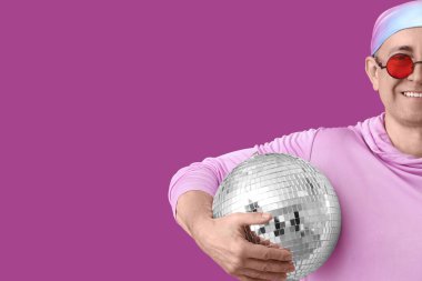 Mor arka planda disko topu olan havalı olgun bir adam, yakın plan.