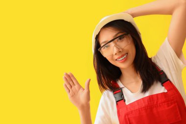 Güzel Asyalı kadın müteahhit sarı arka planda el sallıyor.