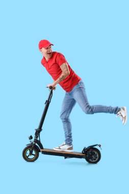 Mavi arka planda elektrikli scooter kullanan genç kurye.