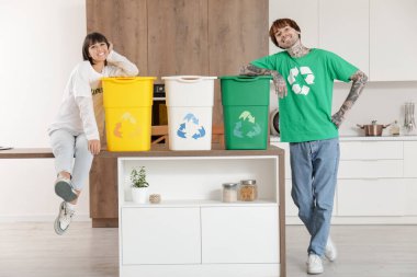 Mutfakta çöp konteynırları olan genç bir çift. Geri dönüşüm kavramı