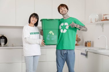 Mutfakta çöp konteynırları olan genç bir çift. Geri dönüşüm kavramı