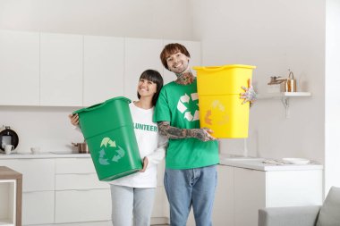 Mutfakta çöp konteynırları olan genç bir çift. Geri dönüşüm kavramı