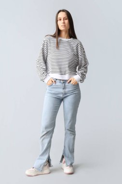 Gri arka planda şık kotlu güzel bir kadın.