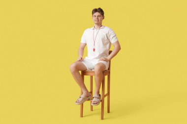 Sarı arka planda ıslık çalan erkek cankurtaran.