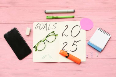 Pembe ahşap arka planda yapılacaklar listesi ve cep telefonu olan bir defter. Yeni yıl hedefleri kavramı