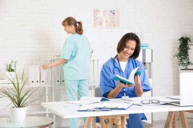 Fotokopi kitabı olan bir kadın stajyer klinikte ders çalışıyor.