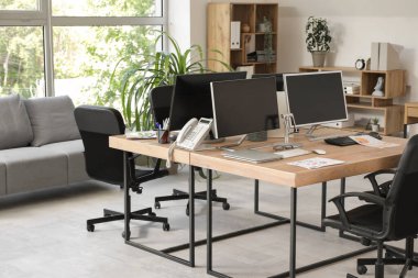 Gri kanepesi, işyeri, bilgisayarı ve koltukları olan şık bir ofis.