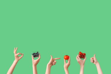 Taze domatesli el hareketi ve yeşil arka planda yaban mersini.