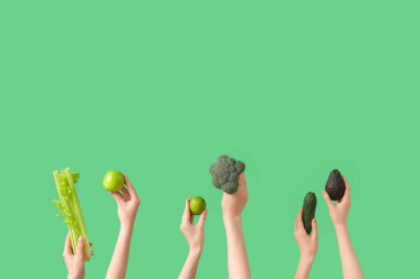 Yeşil arka planda taze elma ve sebzeli eller