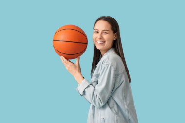 Mavi arka planda basketbol oynayan güzel bir genç kadının portresi.