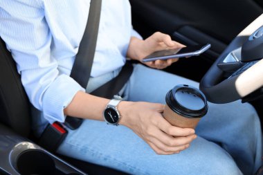 Kahve fincanı ile arabada oturan kadın sürücü, yakın plan.