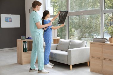 Genç doktorlar klinikte omurga röntgeni üzerinde çalışıyorlar.