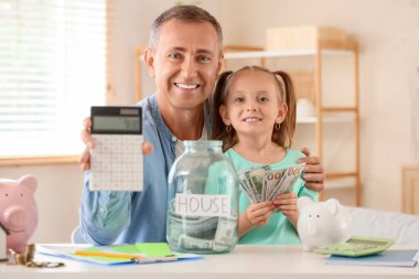 Babası, hesap makinesi ve para kavanozu olan küçük bir kız.