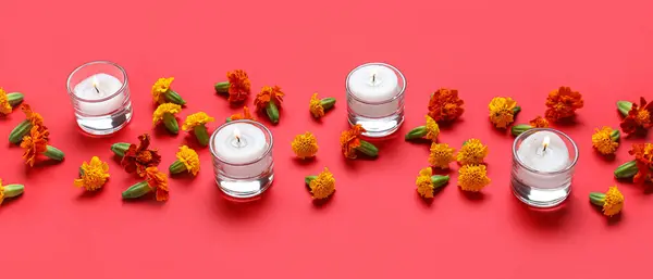 stock image Burning candles and marigold flowers on red background. Divaly celebration