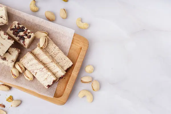 stock image Wooden board with pieces of tasty marble halva on white background