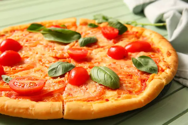 Yeşil ahşap arka planda lezzetli pizza margaritası.