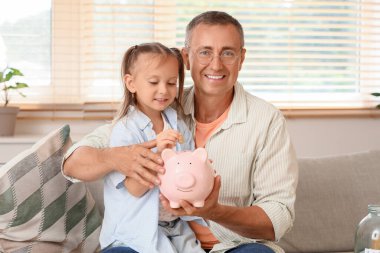 Evde babası ve kumbarasıyla küçük bir kız.