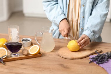 Mutfaktaki masada lavantalı limonata hazırlamak için limon kesen genç bir kadın.
