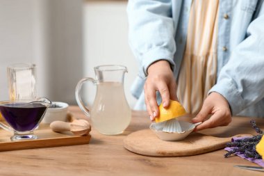 Mutfaktaki masada lavantalı limonata hazırlamak için meyve sıkacağı sıkan genç bir kadın.