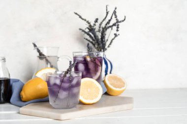 Soğuk lavantalı limonata ve açık ahşap masada limonlar.