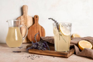 Tahta tahta tahta bir bardak soğuk lavanta limonata ve renkli masa üzerinde çiçekler.
