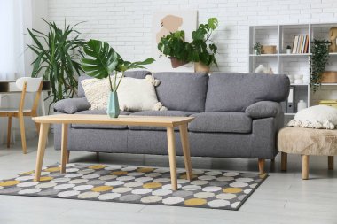 Masada ve şık koltukta tropikal canavar yaprakları olan modern bir oturma odası.