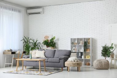 Masada ve şık koltukta tropikal canavar yaprakları olan modern bir oturma odası.